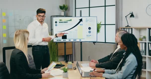 Handsome confident skilled bearded office manager explaining presentation about business concept for successful professional mixed race businesspeople during joint meeting in boardroom — Stock Video