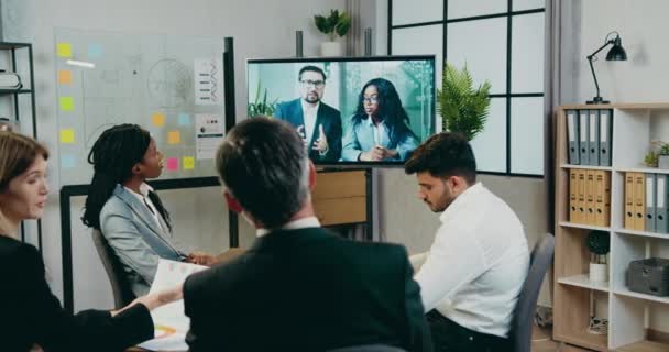 Atraktivní sebevědomí zkušené odpovědné smíšené rasy podnikatelé mají společné video chat konference v televizi s muži a ženami partnery v zasedací místnosti — Stock video