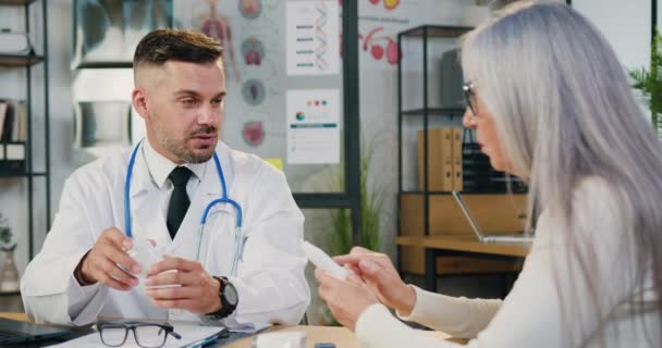 Médico masculino conversa com agge médio doente feminino insalubre durante visita em clínica privada. — Vídeo de Stock