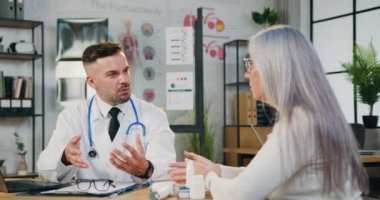 Tıp kürklü doktor, masada oturmuş orta yaşlı kadın hastaya hastalık ya da ameliyat hakkında danışmanlık yapıyor.