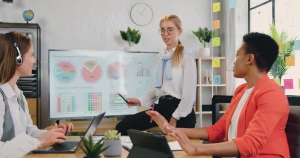 Workflow i kontor, hvor smuk selvsikker venlig erfaren blond kvinde forklarer cirkeldiagram for vellykket motiveret forskelligartet kvindeligt hold i bestyrelseslokalet, front view – Stock-video