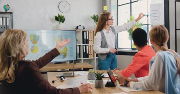 Concepto de negocio donde atractiva mujer responsable experimentada y segura discutiendo con colegas motivadas multiculturales estrategia de negocio conjunta durante la reunión en la sala de oficina — Vídeo de stock