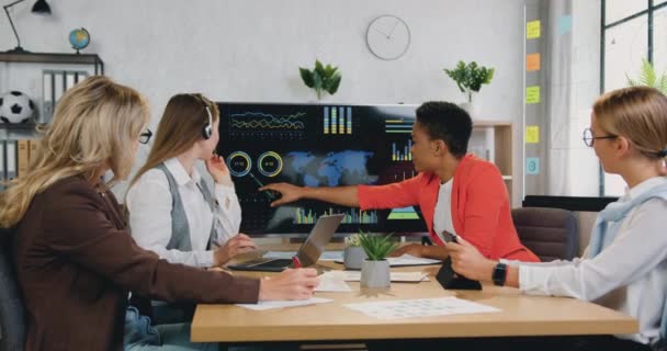 Mujer de negocios afroamericana inteligente bastante sonriente explicando la presentación en pantalla digital para colegas exitosas positivas en la sala de juntas moderna, vista frontal — Vídeos de Stock