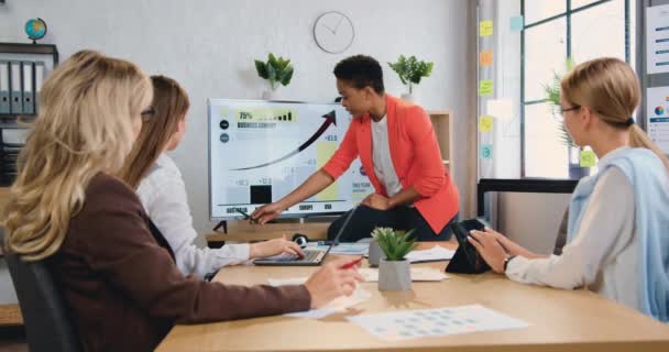 Bela confiante bem sucedida mulher de negócios afro-americana qualificada explicando conceito de negócios no monitor digital para colegas femininos responsáveis motivados atentos durante reunião conjunta em — Vídeo de Stock