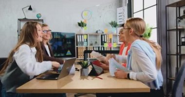 Başarılı evrak işlerini kutlayan ve ofisteki belgelerini başlarından aşağı atan çok ırklı iş kadınlarının mutlu bir şekilde gülümsediği bir başarı konsepti.