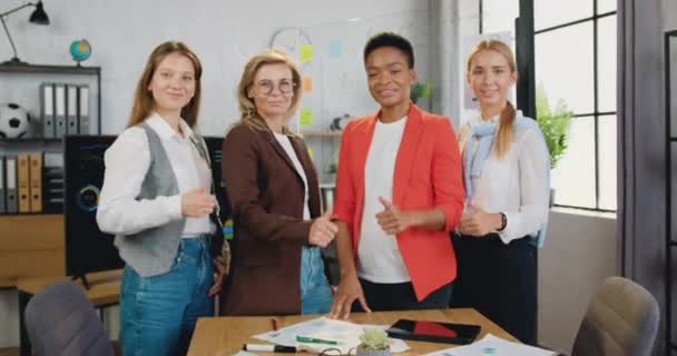 Belo positivo elegante experiente equipe feminina multiétnica de colegas de trabalho corporativos posando na câmera com polegares para cima na sala de escritório moderna — Vídeo de Stock