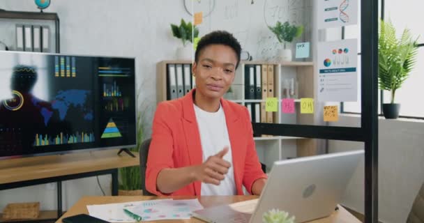 Portré jóképű mosolygós sikeres magasan képzett afroamerikai üzletasszony, amely dolgozik laptop a modern irodában, és bemutatja a jó munka szimbólum a kamerába — Stock videók