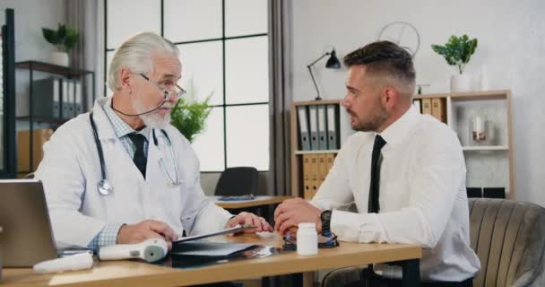 Médico americano maduro conversando com paciente masculino durante aconselhamento em consultório médico. Concepção de cuidados de saúde — Vídeo de Stock