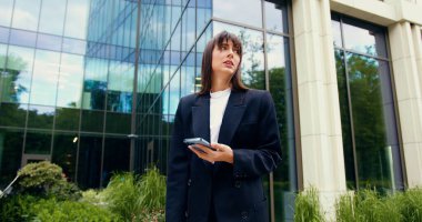 Kafkasyalı genç bir kadın elinde akıllı bir telefonla kötü haberler okuyor ya da açık havada ticari bir binanın önünde dururken cep telefonu uygulamasından hayal kırıklığına uğruyor..