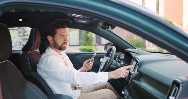 Modern adam şık bir aracın içinde navigasyon ve müzik kuruyor. Teknoloji, seyahat, bağlantı ve modern yaşam tarzı kavramı. Yavaş çekim