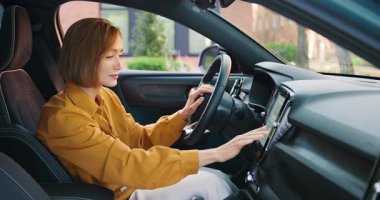 Güzel genç bir kadın modern bir arabanın içinde bir ekrana navigasyon kuruyor, bir yolculuğa hazırlanıyor. Teknoloji, seyahat, bağlantı ve çağdaş yaşam tarzı kavramı. Yavaş çekim