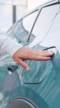 Elektrikli araba şarj aletini boşaltılmış bir araca bağlayan erkek ellerinin yakın çekimi açık havada şarj işlemini başlatıyor..