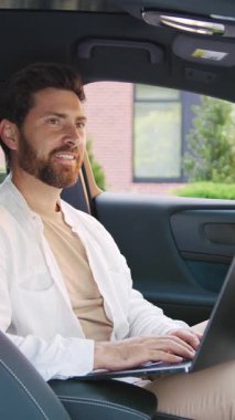 Modern bir ofis binasının yakınında park halindeki arabasında otururken uzaktan bilgisayarla çalışan yakışıklı beyaz adam görevine odaklanmış. Yavaş çekim