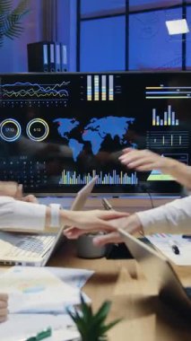 Gülümseyen insanlar çeşitli erkek ve kadın ofis arkadaşları masanın arkasında oturuyor ve akşam ofislerinde elleriyle birlik sembolü oluşturuyorlar.