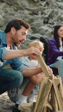 Gülümseyen anne ve kız piknik için yemek hazırlıyorlar, erkek ve oğlan yakacak odun ve ateş yığınının yanında oturup doğada beş araba veriyorlar orman yürüyüşünden önce dinlenmek için piknik molası veriyorlar..