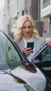 İyi görünümlü, pozitif ve başarılı bir iş kadını. 40 yaşında, resmi giysiler içinde. Cep telefonunda yazı yazıyor. Yavaş çekim