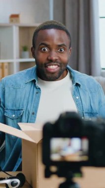 Yakışıklı, mutlu, mutlu, mutlu, sakallı, Afro-Amerikan blogcu. Evde internet kanalı için yeni video kaydedilirken, kartondan aldığı şeyleri gösteren bir blog yazarı.