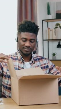 Modern genç blog yazarı video kameranın önünde oturuyor ve güzel ev içi arka plandaki paketleme işlemini kaydediyor.