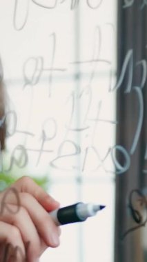 Güzel görünümlü, yaratıcı yetenekli, 35 yaşında sakallı bir işçinin portresi. Cam panonun yanında duruyor ve başlangıç projesini geliştirmek için yeni fikirler kaydediyor.