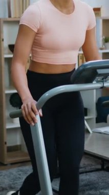 Aktif hayat konsepti, 30 yaşında, sevimli, zayıf, atletik Afrikalı Amerikalı kadın eğitim kıyafetleri içinde, kontrol panelinin düğmelerine basıyor.