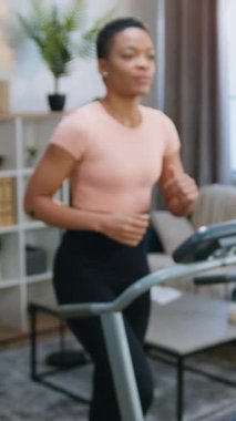 Oldukça pozitif etkin genç Afro-Amerikan kadın antreman kıyafetleri içinde vücudunu sağlıklı ve güçlü tutmak için iç arka planda koşu egzersizleri yapıyor.