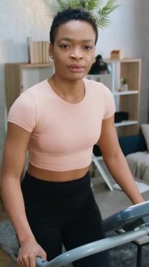 Aktif hayat konsepti. Gündüz vakti rahat oturma odasında spor giyinmiş Afro-Amerikan kadın sporcu kıyafetinin koşu pistine ayak bastığı yer.