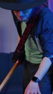 Yakışıklı, iyi modda, siyah şapkalı ve şık güneş gözlüklü 25 yaşında sakallı adam davul çalıyor ve enstrümantal müzik kaydediyor.