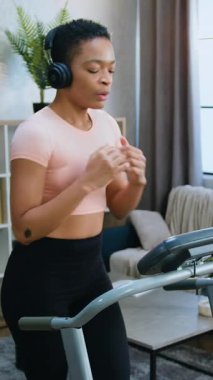 Aktif yaşam tarzı konsepti. Spor giyimli Afro-Amerikan kadın sporcu. Koşu egzersizleri yapıyor ve kulaklıkla şarkılardan keyif alıyor.