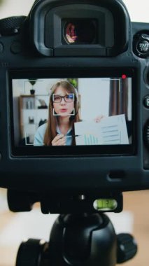 İyi görünümlü, kendine güvenen, kulaklık takmış, internetteki dinleyicileri için video kaydeden ve araştırmasının sonuçlarını açıklayan genç bir kızın kamera görüntüleri.