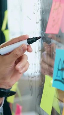 Çalışma akışı konsepti. Ofiste cam pano notları üzerinde çalışan bilinmeyen bir adam renkli yapışkan notlar ve bu tahta üzerinde önemli hatırlatıcılar kaydediyor.