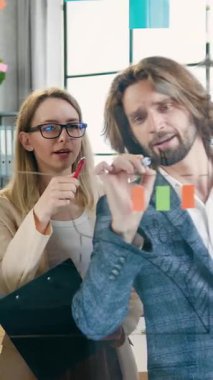 Yeni bir başlangıç projesi yaratan ve bu tahtaya iliştirilmiş yapışkanlar üzerine notlar yazan çekici, aktif, pozitif ve yetenekli kadın ve erkekleri cam tahtada incele