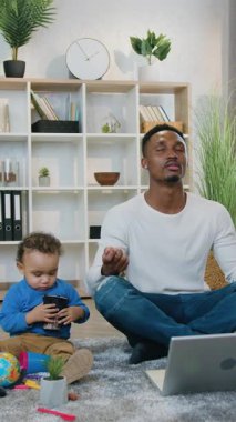 Sevimli, rahat, Afro-Amerikan bir babaya yaklaş. Sevimli, yumuşak halıda oturmuş oyuncaklarla oynayan, gözleri kapalı, ahenkle eğlenen bir babaya.