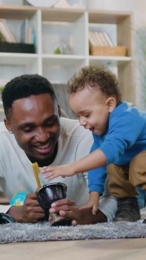 Hoş görünümlü, sevecen, genç, siyah derili bir babanın portresi yumuşak halıda yatar ve davul çalarken hoş, sakin, küçük oğlu keçeli kalem yerine keçeli kalem kullanır.