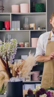 Çiçekçi dükkanında akıllı telefonuna envanter ve not tutan neşeli, yakışıklı bir adamın portresi..