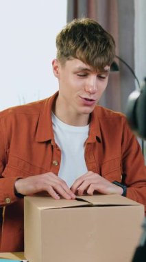 İyi görünümlü bir afallamış, 23 yaşında erkek blogcu evden yayın yapıyor ve kamera önünde satın aldığı siyah kulaklıkları açıyor ve bunları kafasına takıyor.