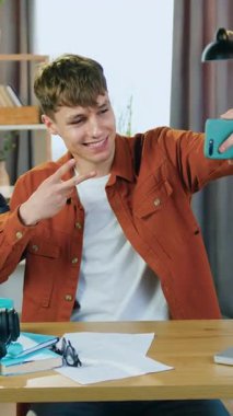 İyi görünümlü, modern, 25 yaşında bir erkeğin portresi. Ev işyerindeki ofisinde oturuyor ve ağır çekimde kendini fotoğraflıyor.