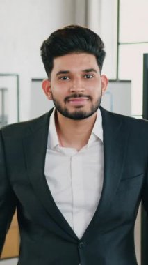 Modern çalışma odasının arka planında kollarını kavuşturarak kameraya poz veren 30 yaşında şık, şık sakallı, resmi giyinmiş, kulaklarında küpeler olan ofis müdürüne yakın durun.