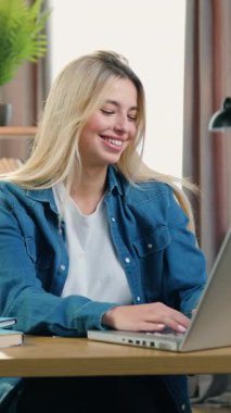 Güzel, kendine güveni tam 25 yaşında, modaya uygun kıyafetleri olan bir kız iş yerinde güzel dekore edilmiş bir ofiste dizüstü bilgisayarında çalışıyor.