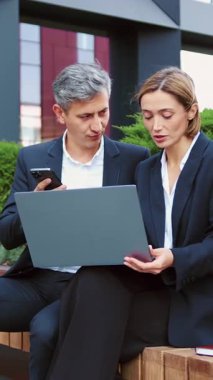 Açık hava restoranındaki bir iş toplantısında kıdemli girişimciler dizüstü bilgisayardaki bir projeyi tartışıyorlar. Erkek ve kadın klavyede konuşuyor ve daktilo kullanıyor. Erkek ve kadın iş tartışıyorlar..