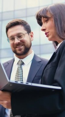 İki iş arkadaşı şirket binasının girişinde dizüstü bilgisayar kullanarak sohbet ediyorlar. İş adamlarını ve iş toplantılarını kabul et