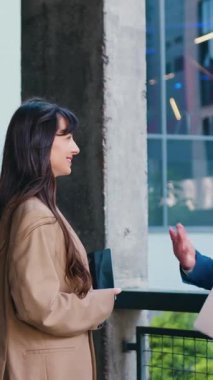 İki iş adamının yan görüşü genç bir kadın ve yaşlı bir adam, modern bir ofis binasının önünde duruyorlar, fikir alışverişinde bulunuyorlar ve önemli işleri analiz ediyorlar.