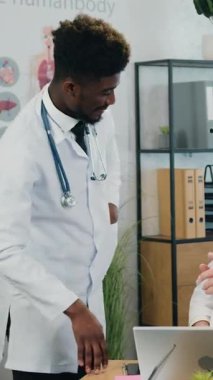 Beyaz önlüklü, kendine güveni yüksek, çok yönlü tıp çalışanları modern tıp atölyesindeki danışmanlık sırasında 65 yaşındaki beyaz saçlı profesyonel hastane başkanıyla sohbet ediyorlar.