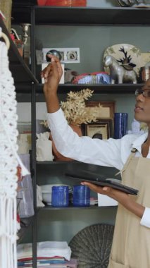 Çekici, kendine güvenen Afro-Amerikan kadın satıcı el yapımı hediyelik eşya dükkanında çalışıyor ve malları sayıyor, gözden geçiriyor ve tablet üzerinde fark ediyor.