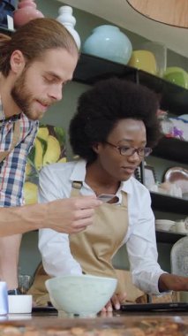 Potansiyel alıcılar için banka hesap bilgilerini çevrimiçi siparişlerle girerken, el yapımı güzel hediyelik eşya dükkanının sempatik, dost canlısı, çok ırklı, profesyonel satıcıları dizüstü bilgisayarda birlikte çalışıyor.