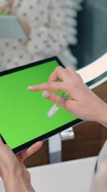 Woman holds a laptop pc with a green chromakey screen in her hands. Girl using smartphone with chroma-key or green screen touchscreen at luxury bathroom. Slow motion.