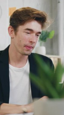 Çekici, başarılı, zeki, siyah ceketli 25 yaşında bir adamın çalışma odasında oturduğu ve dizüstü bilgisayarda klavye kullandığı bir iş konsepti.