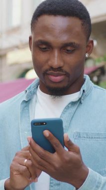 Güzel görünümlü, modern sakallı, modaya uygun gençlik kıyafetleri içinde, rahat bir sokak kafesi ve telefon uygulamaları olan, 4K