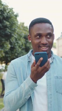 Çekici, mutlu, 30 yaşında, siyah tenli, şık sakallı, modaya uygun sakallı, şehir sokaklarında yeşil bitkilerle gezen ve akıllı telefondan arkadaşıyla görüntülü sohbet eden modern bir adam.