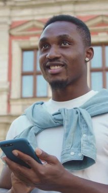 Çekici kaygısız, 30 yaşında, modaya uygun sakallı, küçük yuvarlak küpeli, antik mimari binaların arka planına mesaj yazan bir adam.