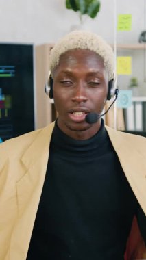 İyi görünümlü, sorumluluk sahibi, kablosuz kulaklıklı Amerikalı genç bir adam atölyede web kamerasının önünde oturuyor ve izleyiciler için çevrimiçi yayın yapıyor.